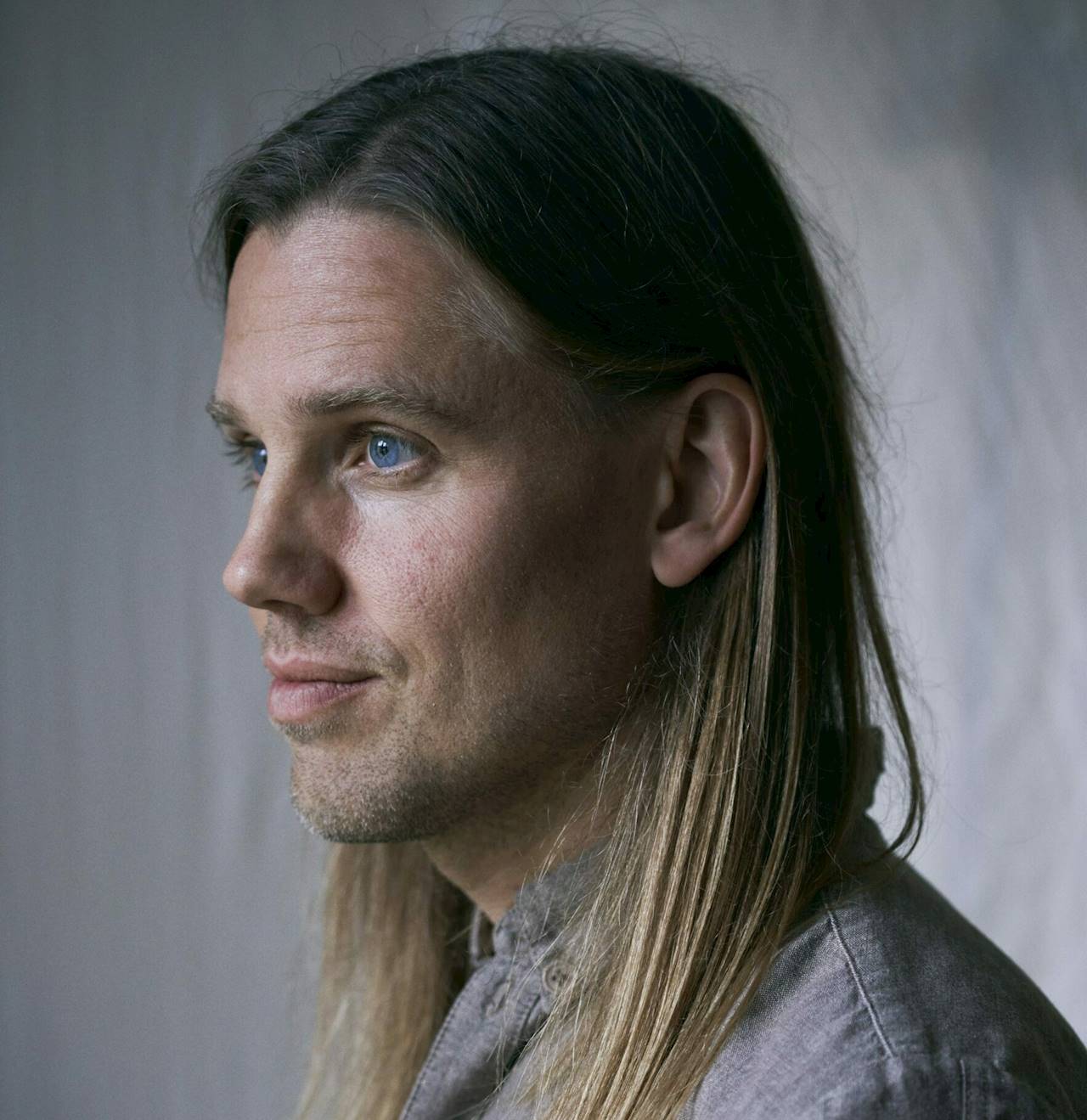 Bild av en man i skjorta med axellångt hår. Bilden är tagen i profil och i gråa toner.