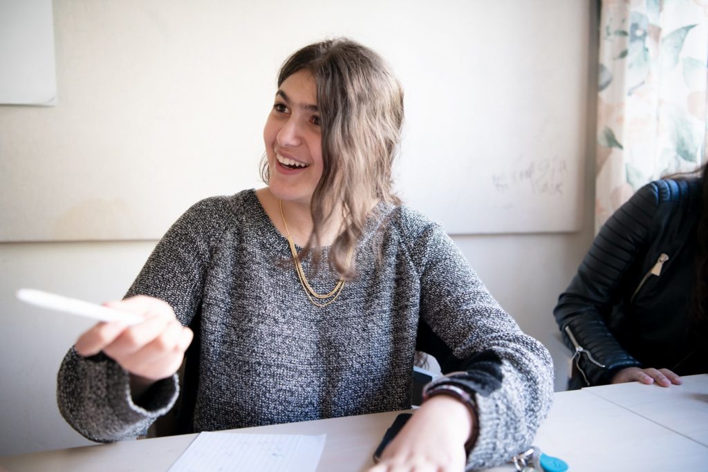 Kvinna ler och pekar med penna vid ett bord