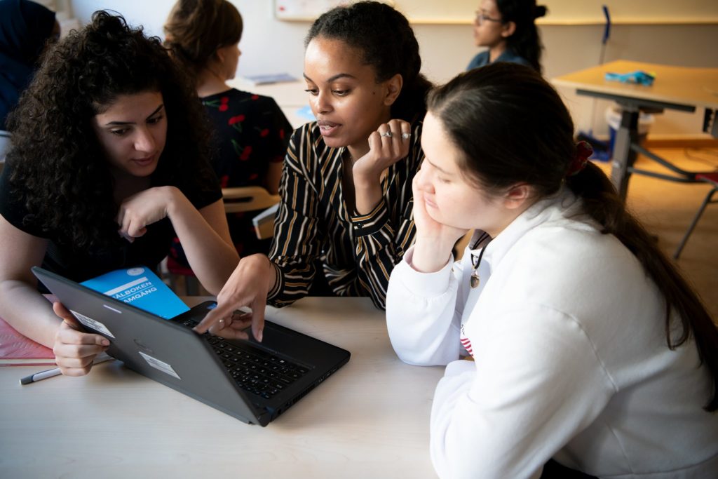 Tre personer framför en laptop