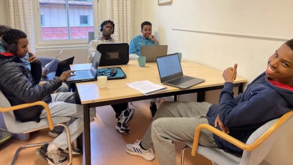 Fyra elever sitter vid ett bord med datorer framför sig