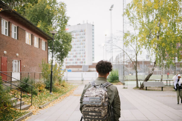 Bild på pojke med ryggsäck på skolgård på väg att lämna skolan.