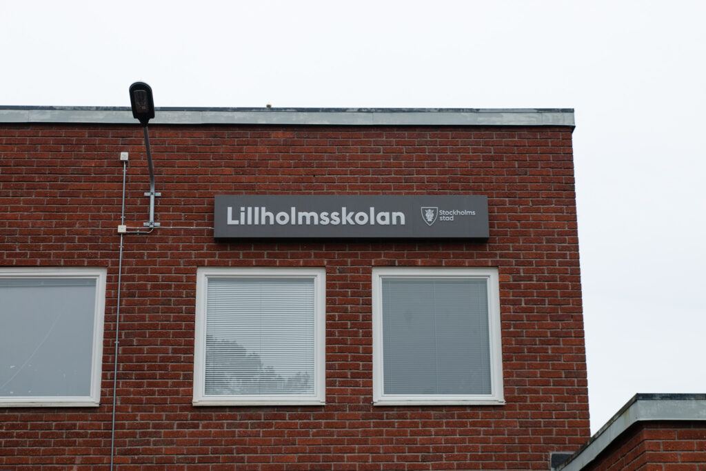 Bild på skolbyggnad i rött tegel. På byggnaden syns en skylt där det står "Lillholmsskolan"